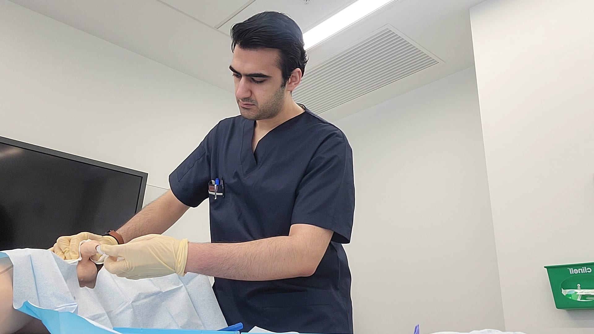 Arvin Ardakani in clinical scrubs performing a procedure